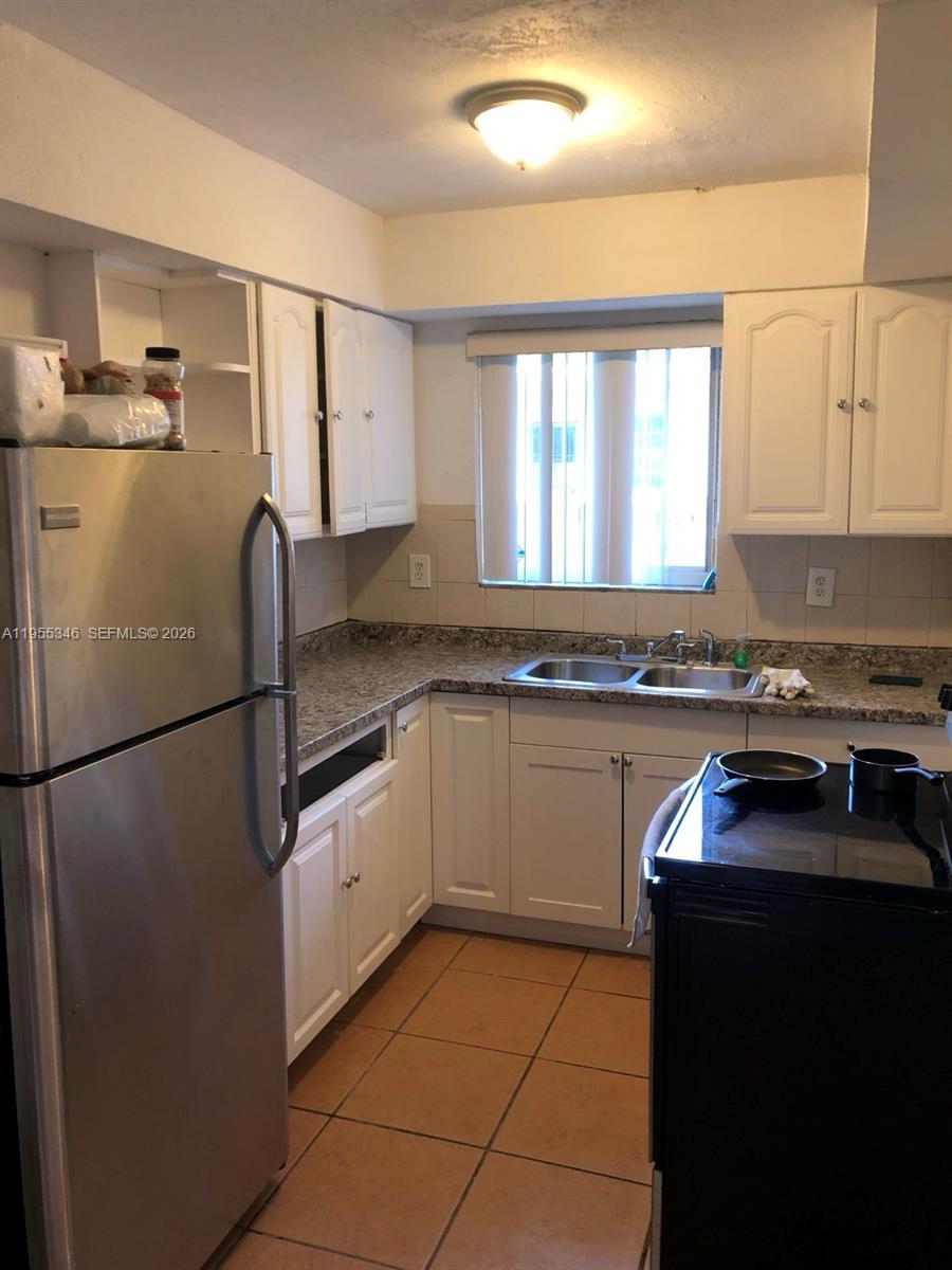 A kitchen features white cabinets, granite countertops, stainless steel appliances, and tile flooring — 5411 NW 6th Ave, Miami FL 33127, MIAMI, FL