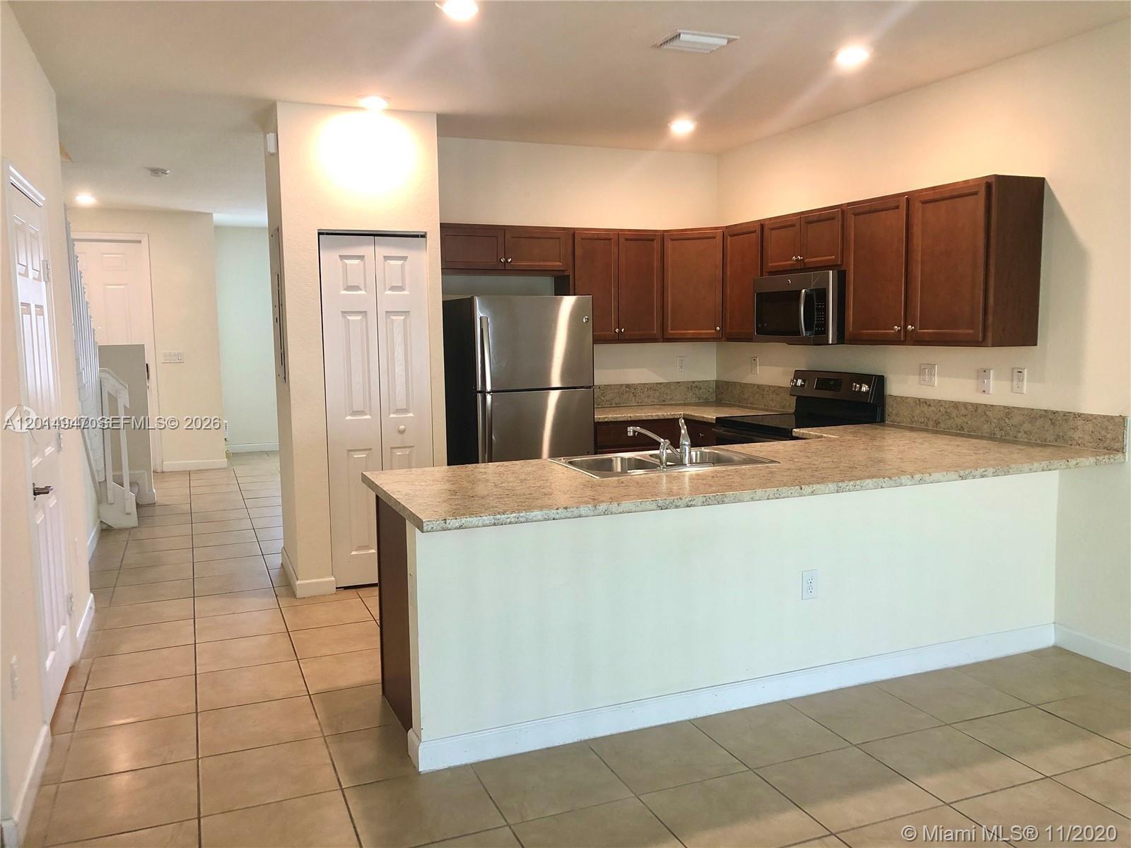 A kitchen features wood cabinets, stainless steel appliances, and a peninsula with a laminate countertop — 9213 W 33rd Way, Hialeah FL 33018, HIALEAH, FL