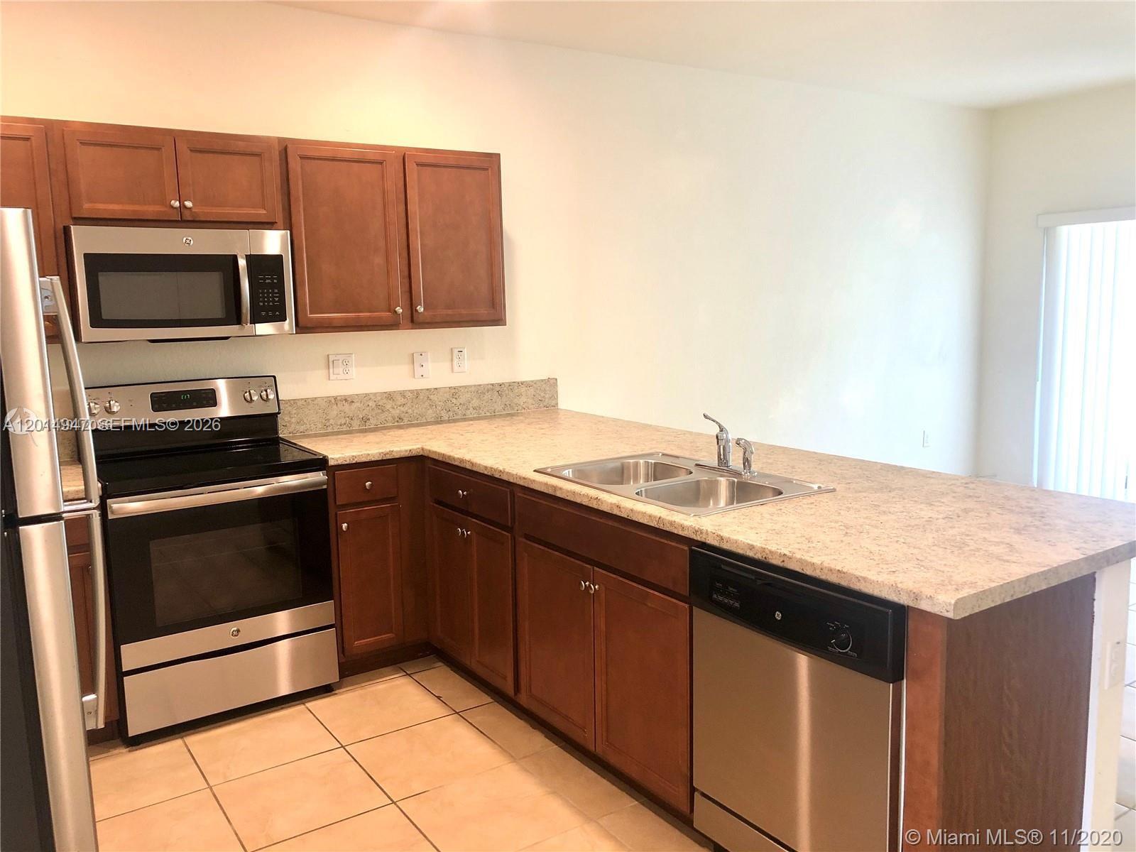 A kitchen features wooden cabinets, stainless steel appliances, and a light-colored countertop — 9213 W 33rd Way, Hialeah FL 33018, HIALEAH, FL