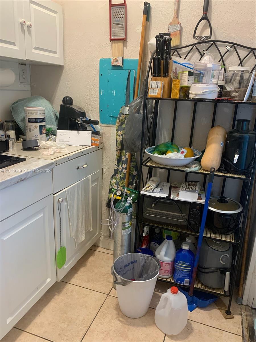 A kitchen corner features white cabinets, a metal shelving unit, and various household items — 1495 SW 131st AVE, Miami FL 33184, MIAMI, FL