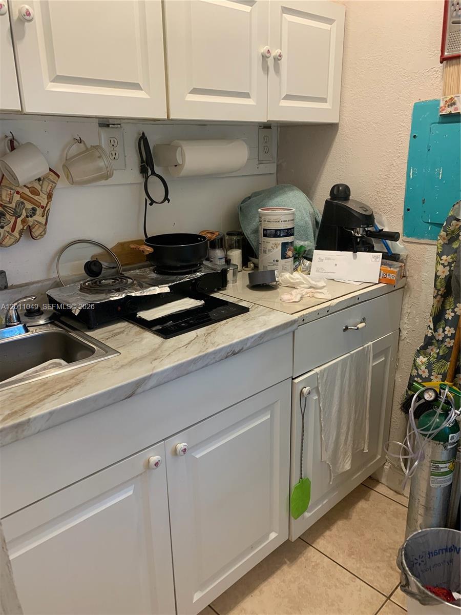 A small kitchen features white cabinets, a marble-patterned countertop, and a portable electric stove — 1495 SW 131st AVE, Miami FL 33184, MIAMI, FL