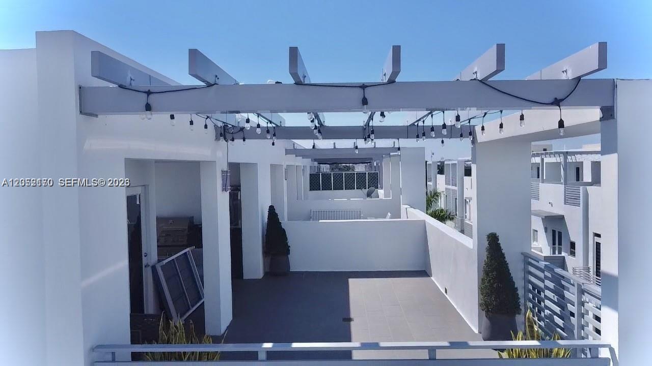 This rooftop terrace features a white pergola with string lights and tiled flooring — 9151 NW 33rd St, Doral FL 33172, DORAL, FL