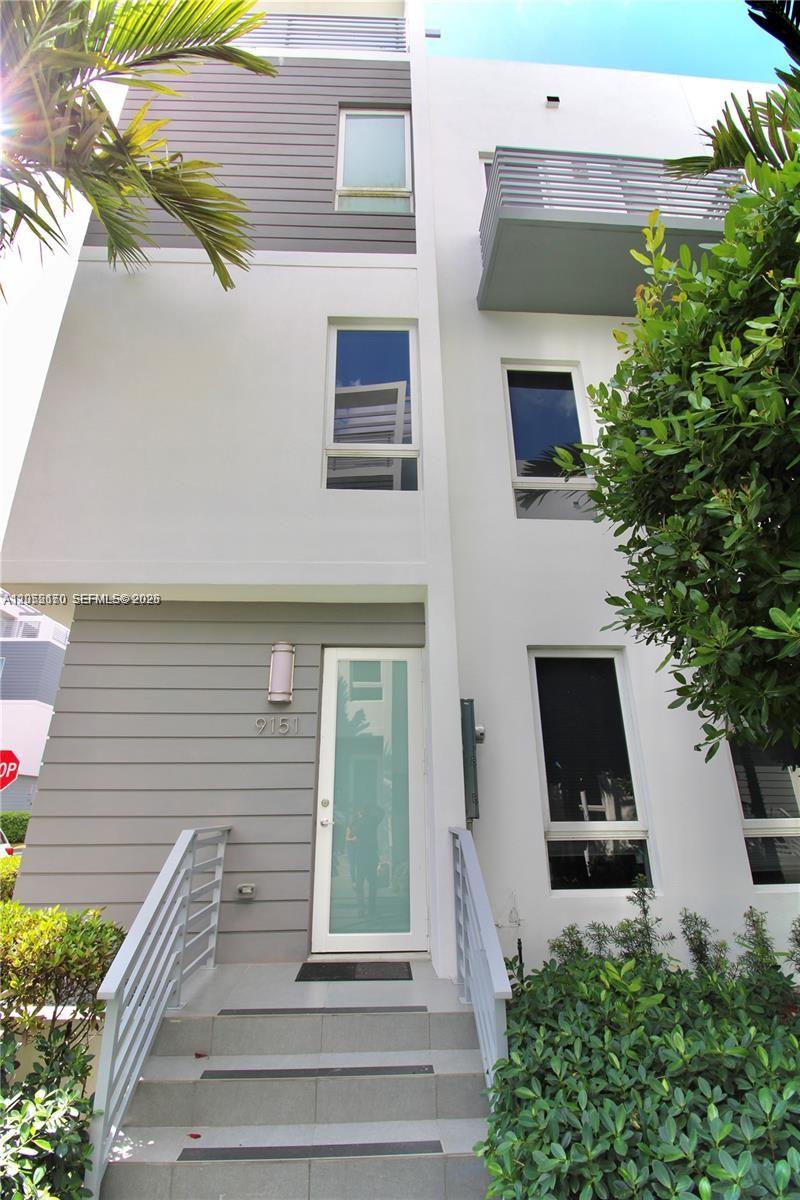 A modern three-story townhouse exterior features gray siding, white stucco walls, and a glass-paneled door — 9151 NW 33rd St, Doral FL 33172, DORAL, FL
