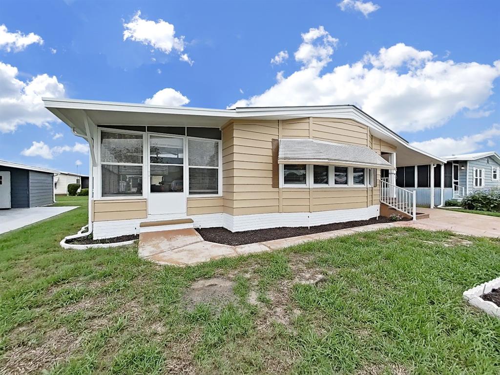 A tan mobile home with a screened-in porch, white trim, and a concrete walkway — 5083 LODGEWOOD DR, LAKELAND, FL