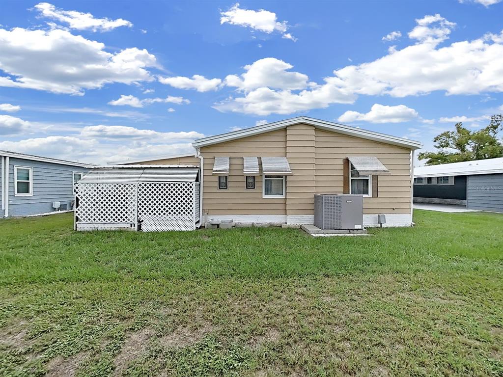 The exterior of a tan mobile home features white lattice skirting and an air conditioning unit — 5083 LODGEWOOD DR, LAKELAND, FL