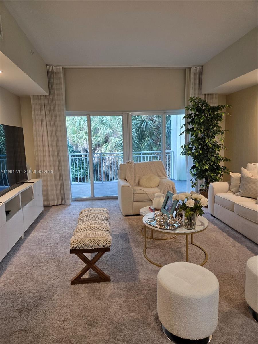 A living room features a white sofa, armchair, coffee tables, and a sliding glass door — 5300 NW 87th Ave # 416, Doral FL 33178, DORAL, FL
