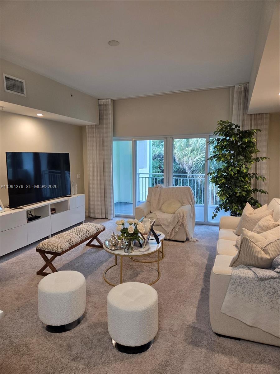 A living room features a television, white furniture, a coffee table, and a balcony view — 5300 NW 87th Ave # 416, Doral FL 33178, DORAL, FL