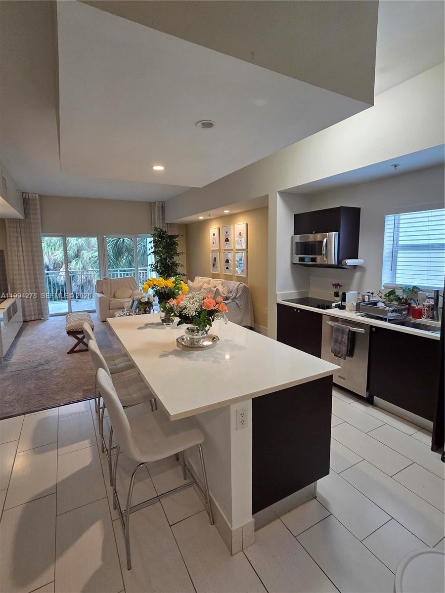 A modern kitchen with a white island and dark cabinets opens into a living area — 5300 NW 87th Ave # 416, Doral FL 33178, DORAL, FL