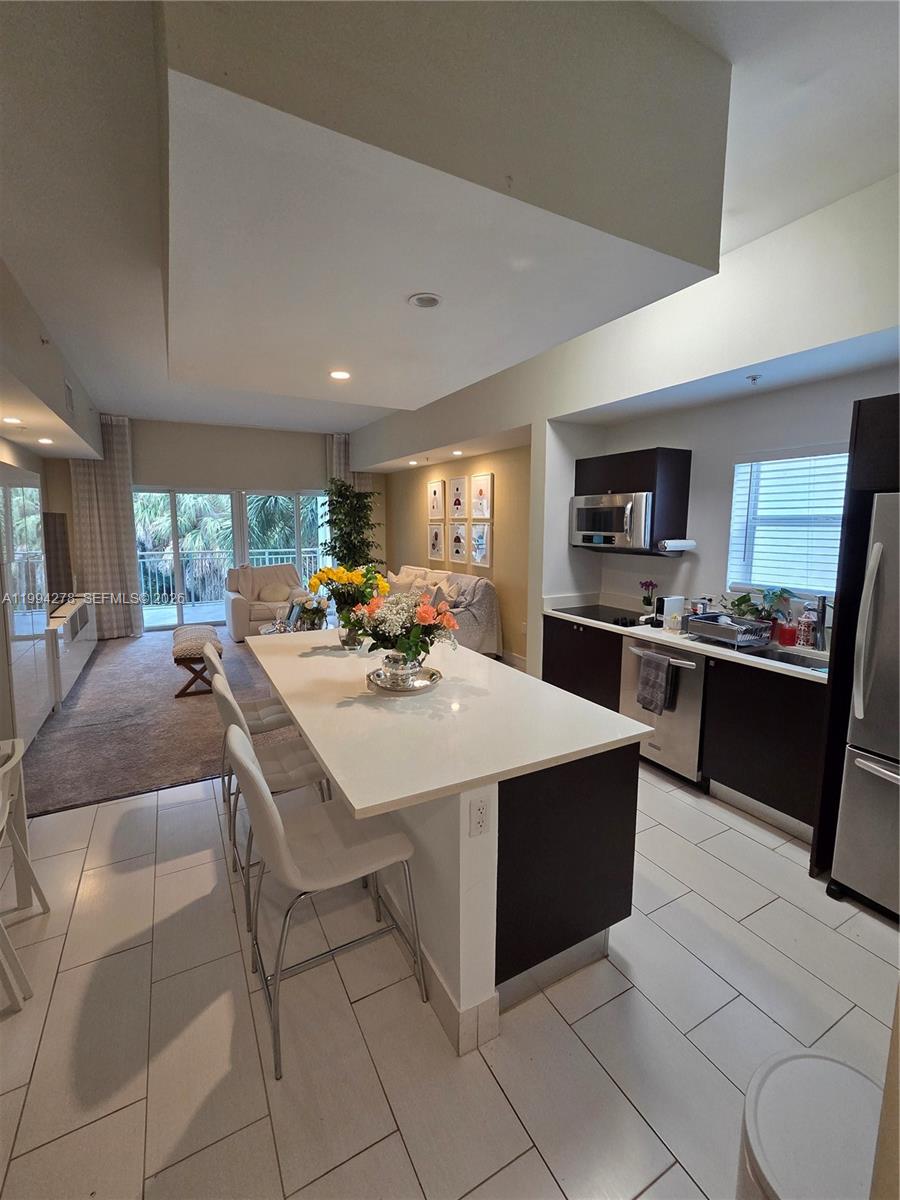 A modern kitchen with a white island and dark cabinets opens into a living area — 5300 NW 87th Ave # 416, Doral FL 33178, DORAL, FL