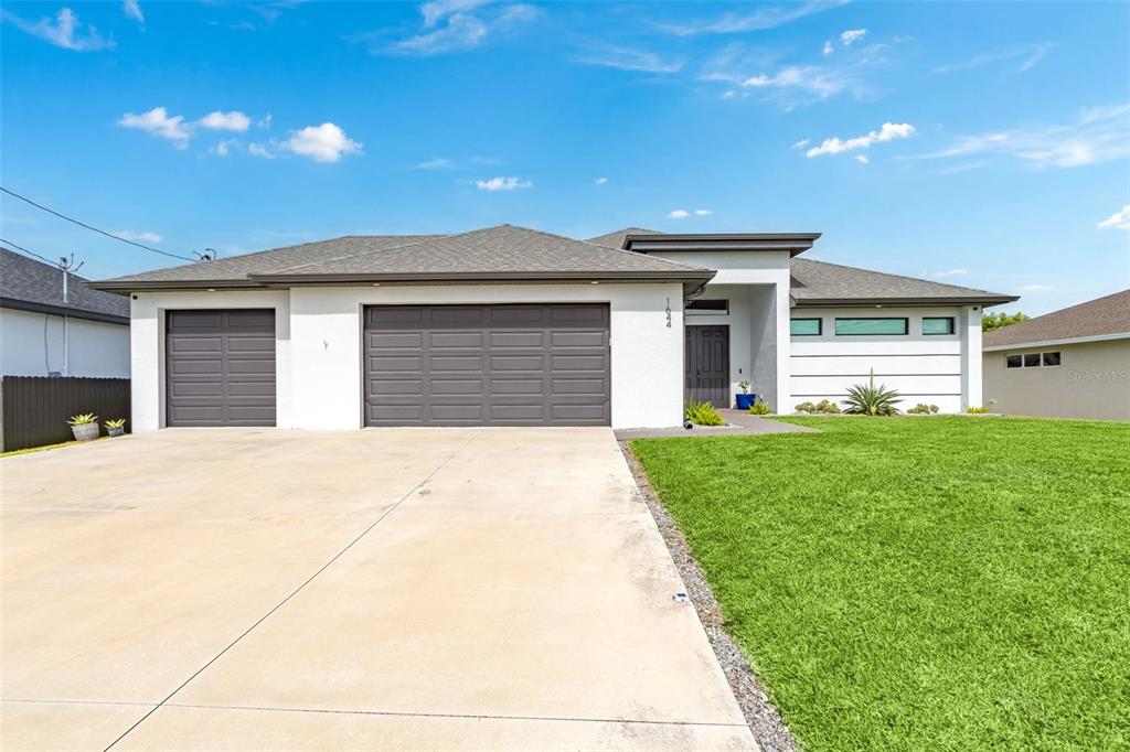 A single-story house with a white exterior, gray roof, and a three-car garage — 1644 NW 37TH AVENUE, CAPE CORAL, FL