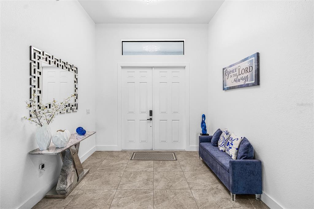A bright entryway features white walls, tile flooring, a console table, and a blue sofa — 1644 NW 37TH AVENUE, CAPE CORAL, FL