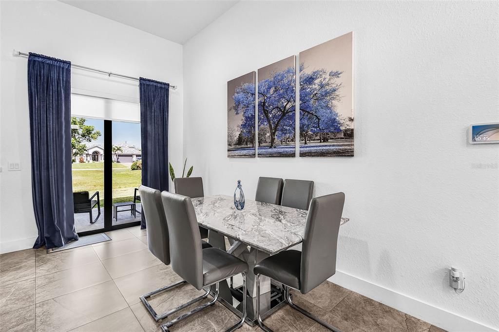 A dining area features a marble-topped table, gray chairs, blue curtains, and wall art — 1644 NW 37TH AVENUE, CAPE CORAL, FL