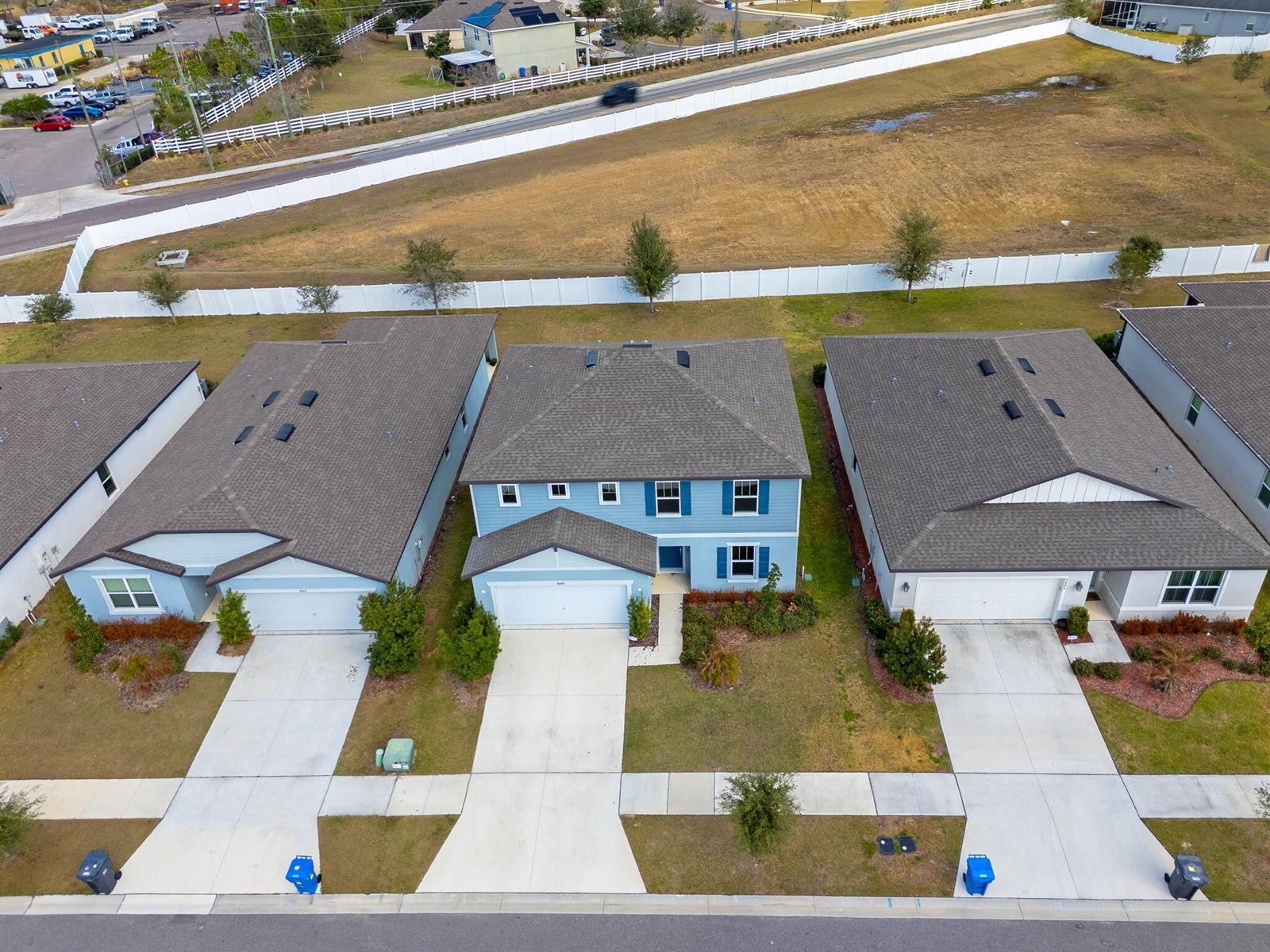 An aerial view shows three suburban houses with driveways and lawns along a paved street — 9644 Summers Cay Circle, FL 33592, FL