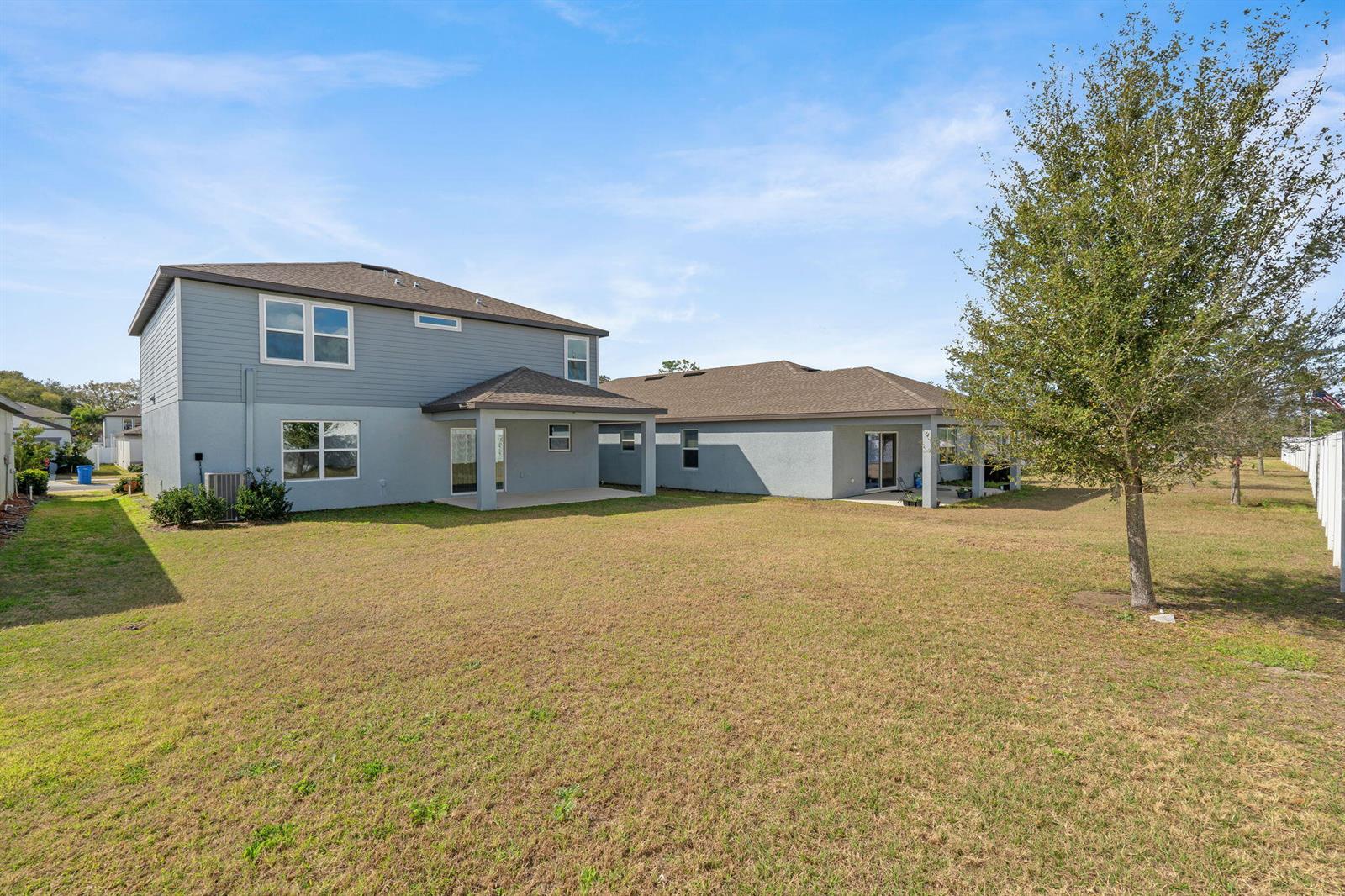 The exterior of a two-story gray house with a backyard and a covered patio — 9644 Summers Cay Circle, FL 33592, FL