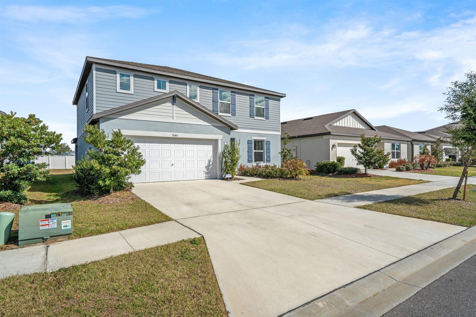 A two-story house with blue siding and a concrete driveway sits on a suburban street — 9644 Summers Cay Circle, FL 33592, FL