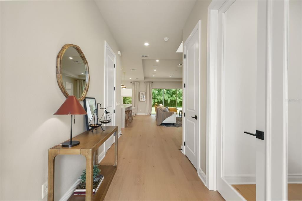 A hallway with light wood floors leads to an open-concept living area and kitchen — 344 AMBERSWEET PLACE, LAKE MARY, FL