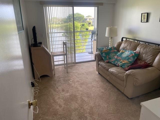 A living room features a beige sofa, a television on a stand, and a sliding door — 117 Brighton C # 117, Boca Raton FL 33434, BOCA RATON, FL