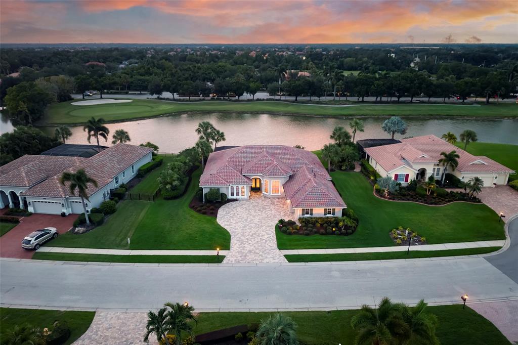 An aerial view of a single-story house with a tiled roof facing a golf course lake — 10625 RESTORATION TERRACE, BRADENTON, FL