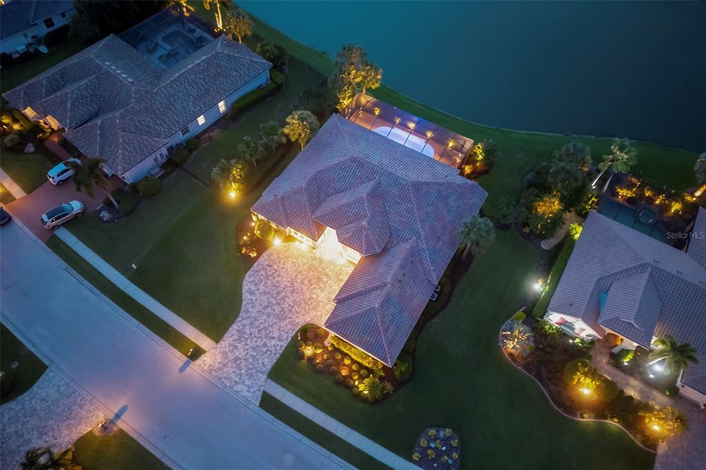 An aerial view shows a residential house with a tiled roof, pool cage, and driveway — 10625 RESTORATION TERRACE, BRADENTON, FL