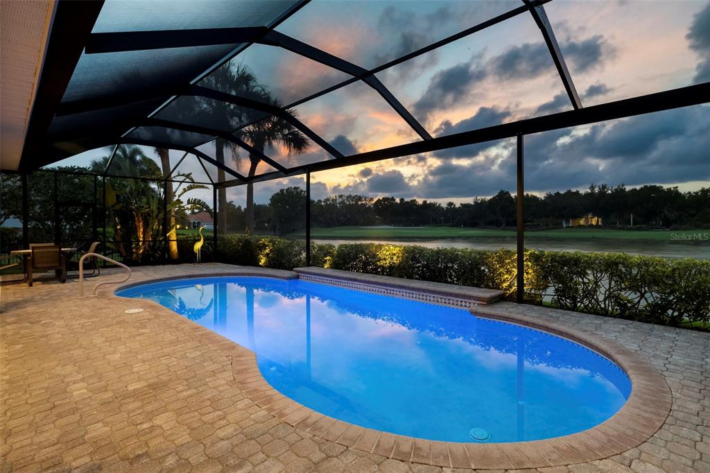 A screened-in pool patio overlooks a golf course at sunset — 10625 RESTORATION TERRACE, BRADENTON, FL