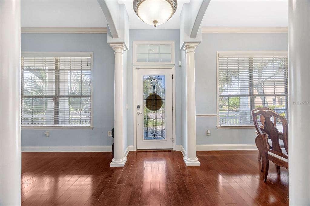 A foyer with hardwood floors, two white columns, and a glass-paneled front door — 4303 TOKOSE PLACE, LAKELAND, FL