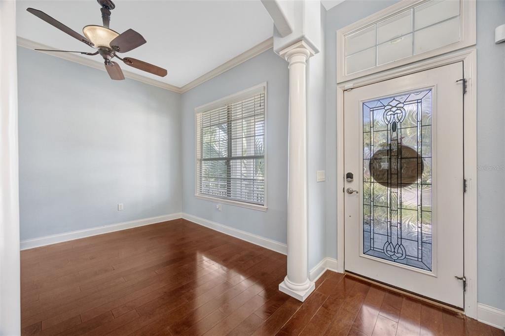An entryway with hardwood floors, a white column, a ceiling fan, and a glass-paneled door — 4303 TOKOSE PLACE, LAKELAND, FL