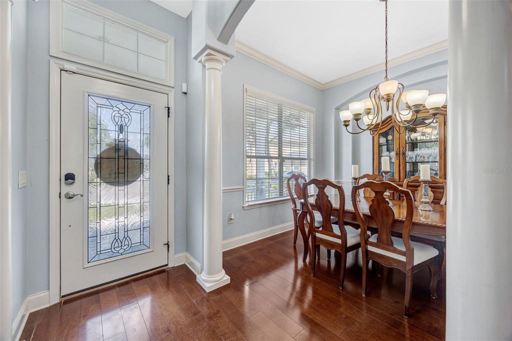 A dining room with hardwood floors, a chandelier, and a front door with glass inserts — 4303 TOKOSE PLACE, LAKELAND, FL