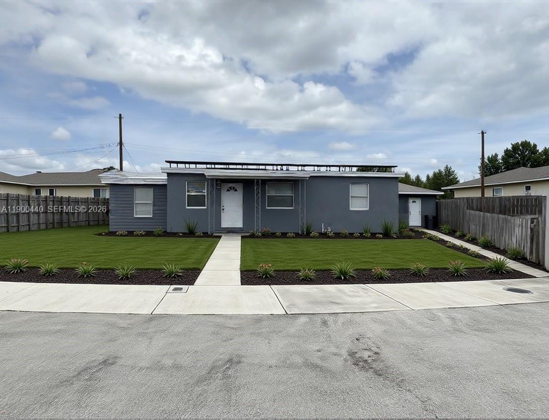 A single-story gray house with a white door and a manicured lawn — 1885 NE 53rd St, Pompano Beach FL 33064, POMPANO BEACH, FL