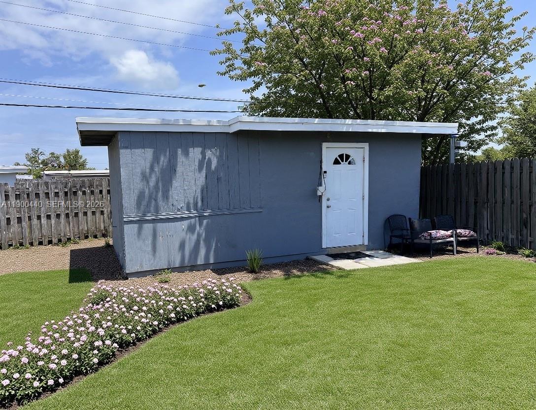 A gray shed with a white door sits in a yard with a flower bed — 1885 NE 53rd St, Pompano Beach FL 33064, POMPANO BEACH, FL