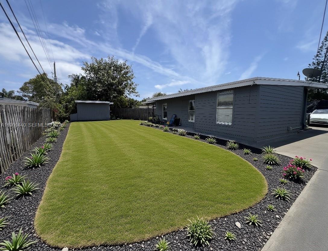 A gray house features a manicured lawn bordered by black gravel and small plants — 1885 NE 53rd St, Pompano Beach FL 33064, POMPANO BEACH, FL