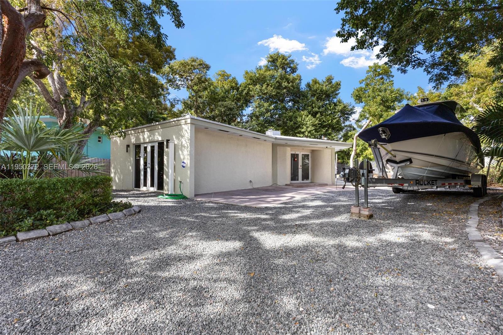 A gravel driveway leads to a one-story house with a boat parked on a trailer — 157 Navajo St, Tavernier FL 33070, TAVERNIER, FL