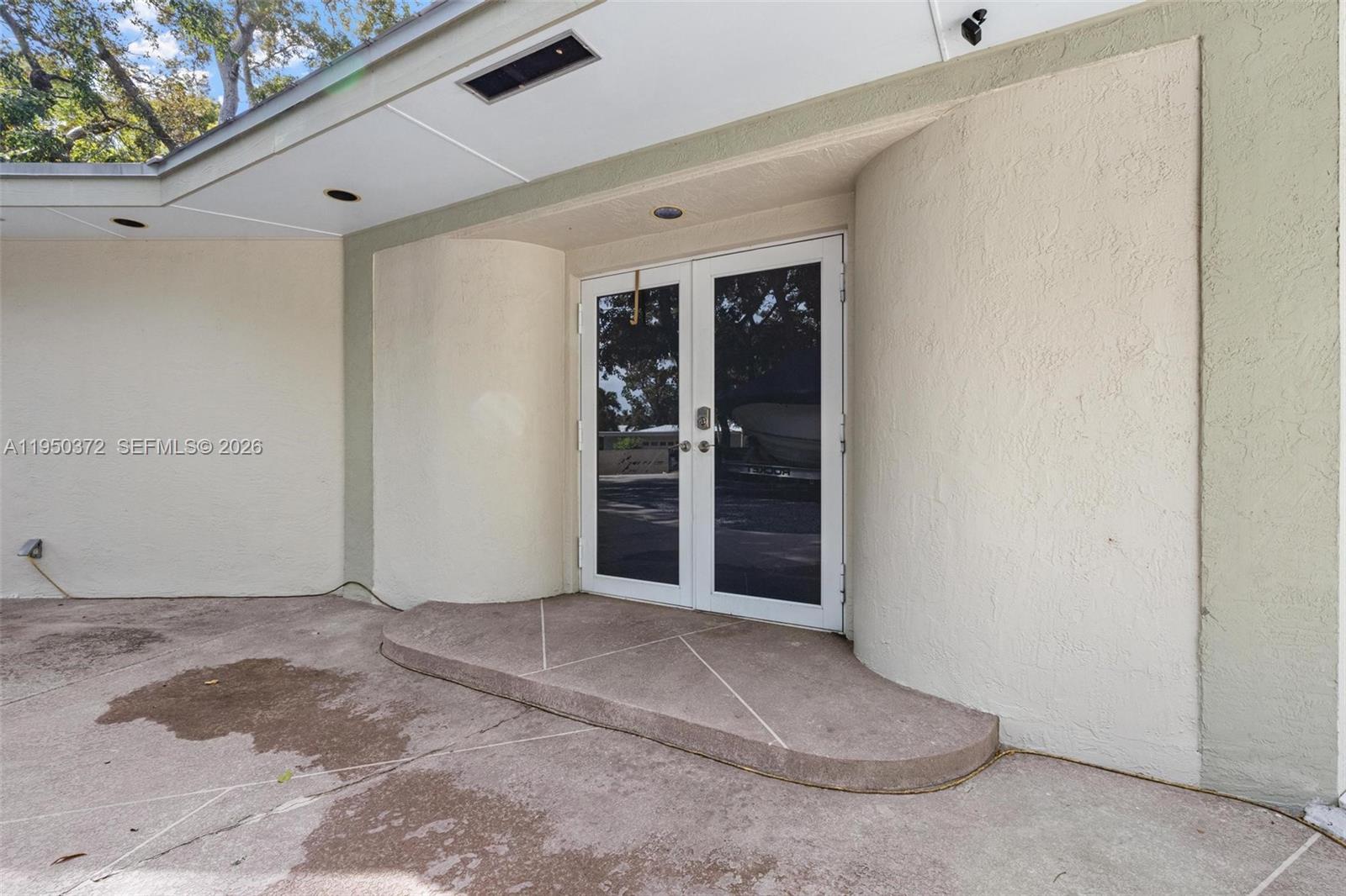 A set of double glass doors is centered on a curved, stucco-finished exterior wall — 157 Navajo St, Tavernier FL 33070, TAVERNIER, FL