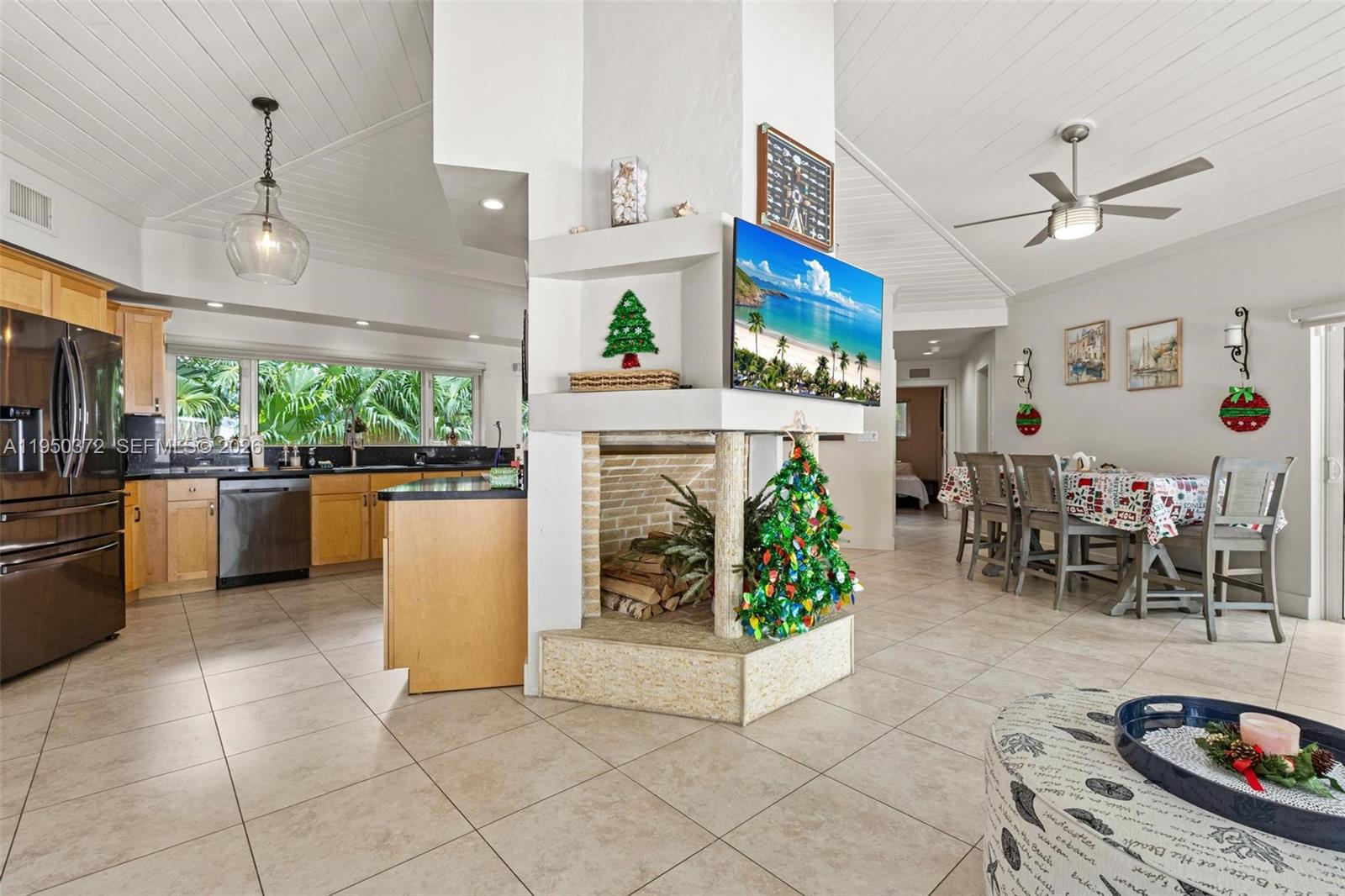 An open-concept living area features a central fireplace, a kitchen with wood cabinets, and dining — 157 Navajo St, Tavernier FL 33070, TAVERNIER, FL