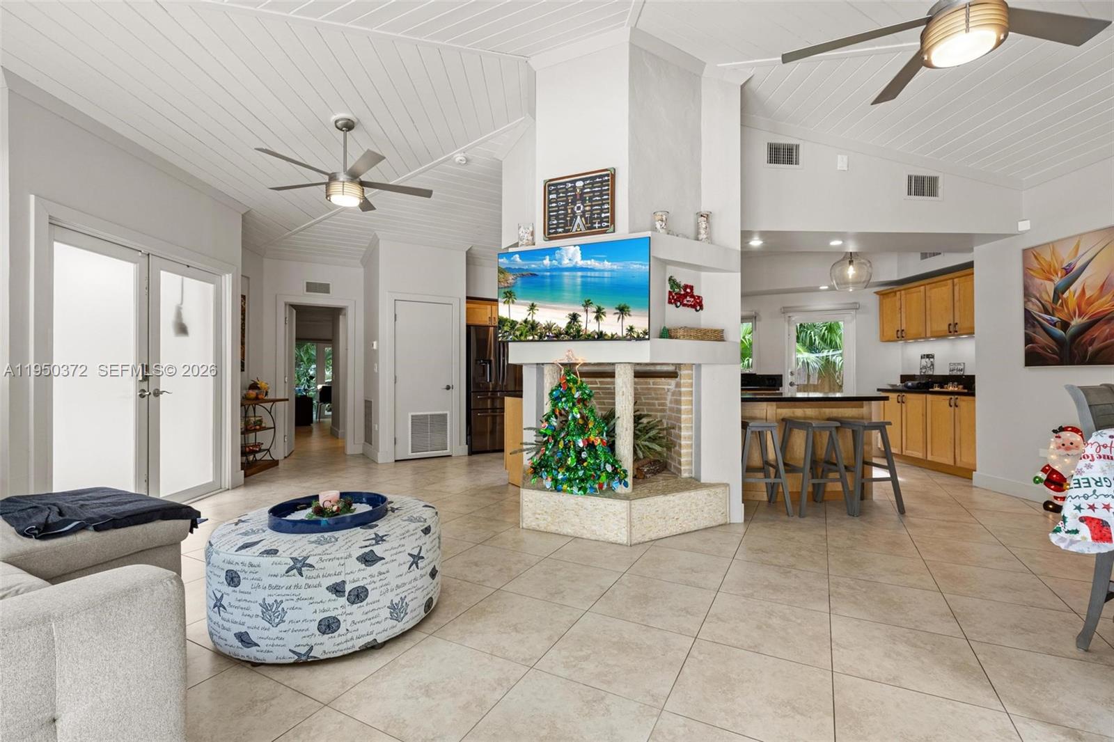 A living room with a central fireplace, tile flooring, and an open kitchen area — 157 Navajo St, Tavernier FL 33070, TAVERNIER, FL