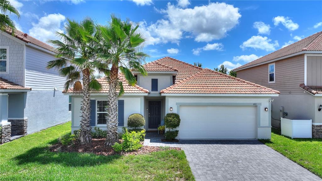 A single-story house with a tiled roof, a two-car garage, and two palm trees — 1111 OAK BLUFF DRIVE, DAVENPORT, FL