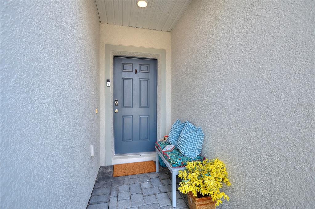 A blue front door sits at the end of a small, covered outdoor entryway — 1111 OAK BLUFF DRIVE, DAVENPORT, FL