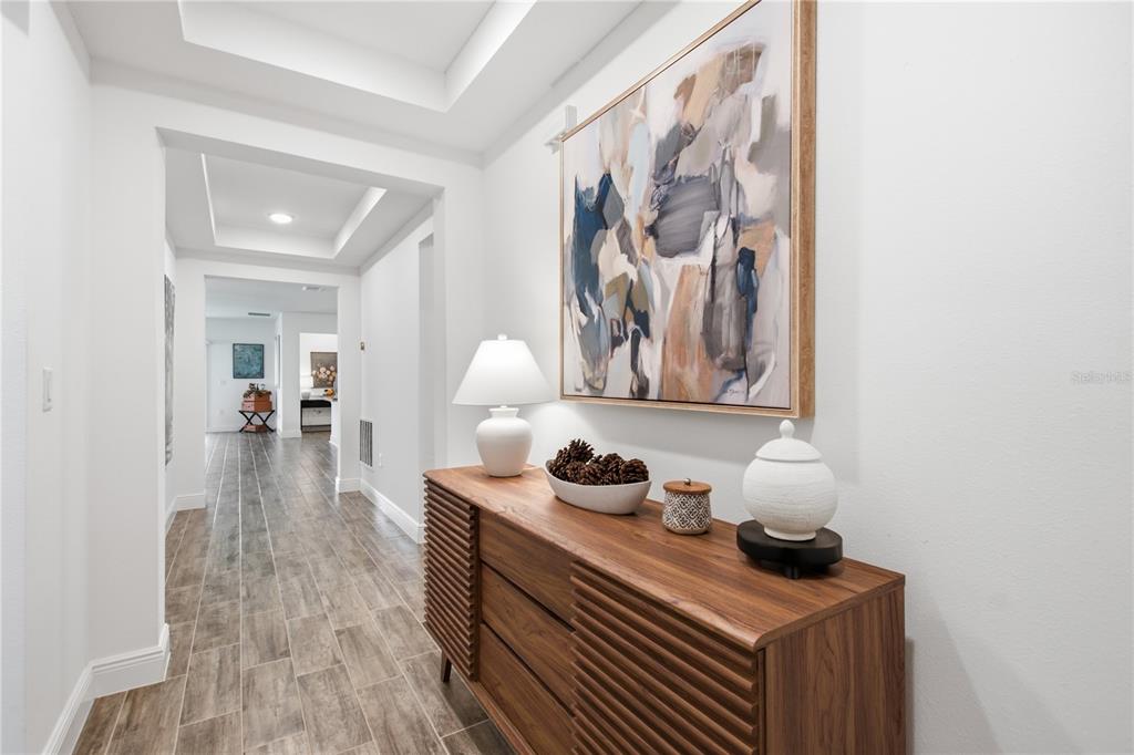 A hallway features wood-look tile flooring, a wooden console table, and a large abstract painting — 1111 OAK BLUFF DRIVE, DAVENPORT, FL