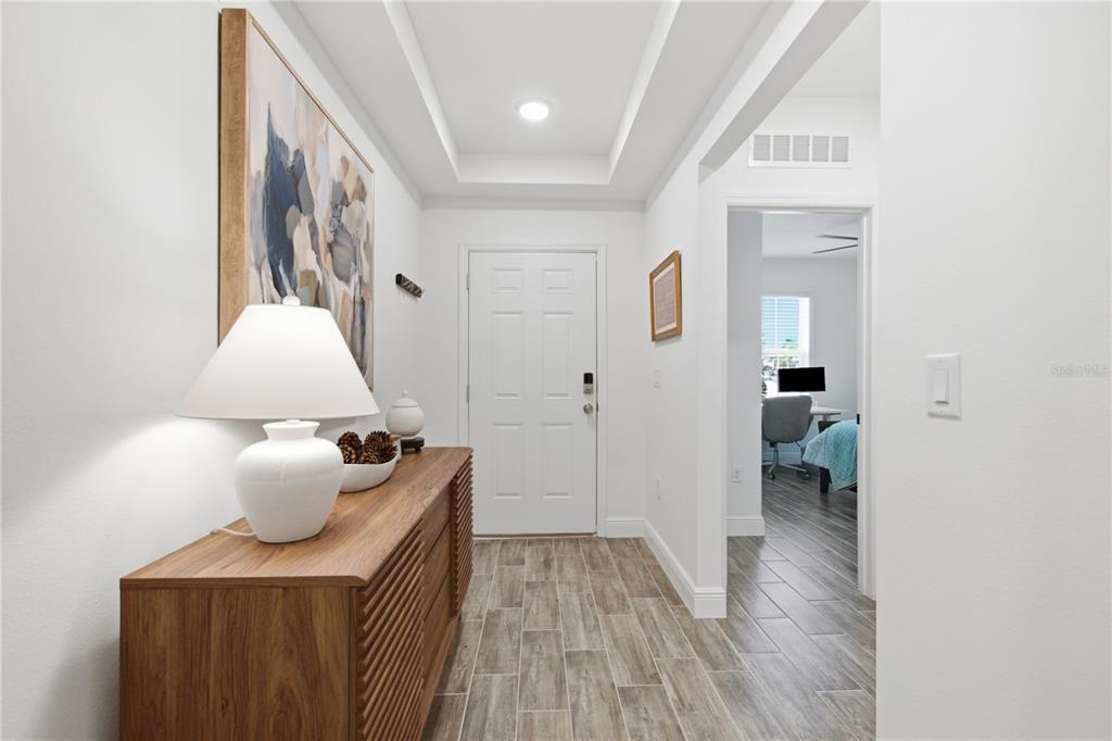 A bright entryway features a wood console table, a white lamp, and wood-look tile flooring — 1111 OAK BLUFF DRIVE, DAVENPORT, FL
