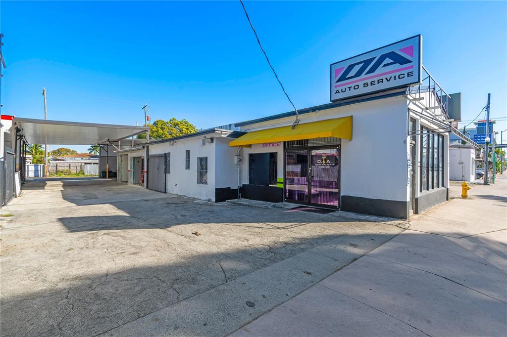 A white commercial auto service building features a yellow awning and a large rooftop sign — 3219 SW 8TH STREET, MIAMI, FL