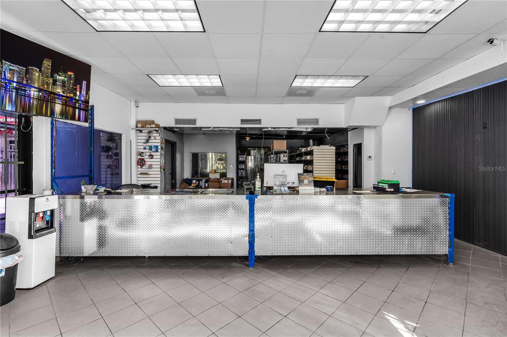 A commercial space features a long service counter with diamond-plate metal paneling and tile flooring — 3219 SW 8TH STREET, MIAMI, FL