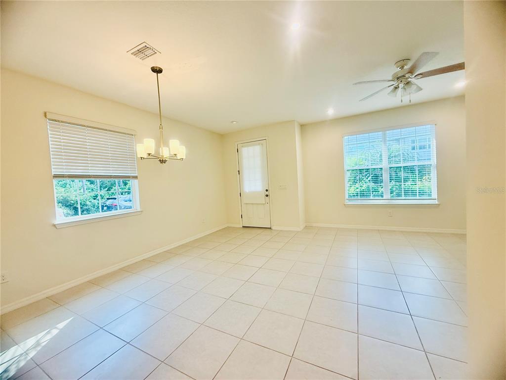 A dining area with tile flooring, a chandelier, a ceiling fan, and two windows — 8878 HERENCIA ALLEY, WINDERMERE, FL