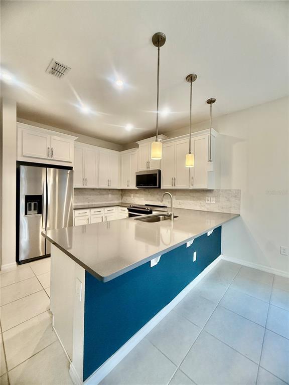 A kitchen features white cabinets, stainless steel appliances, a gray countertop, and a blue island — 8878 HERENCIA ALLEY, WINDERMERE, FL