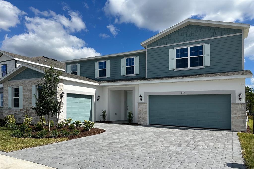 A two-story house with blue siding, stone accents, and a paved driveway — 761 FARFIELDS STREET, DELAND, FL