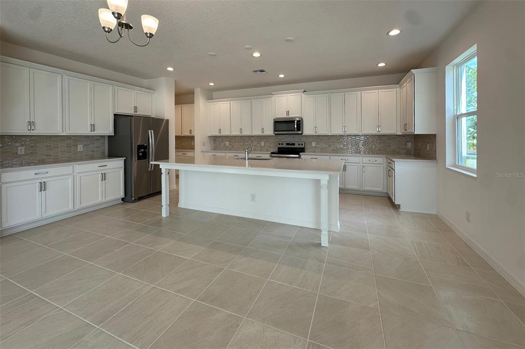 A kitchen with white cabinets, stainless steel appliances, a center island, and tile flooring — 761 FARFIELDS STREET, DELAND, FL