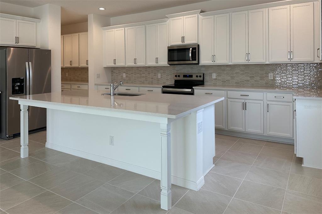 A kitchen with white cabinets, a large island, stainless steel appliances, and light tile flooring — 761 FARFIELDS STREET, DELAND, FL