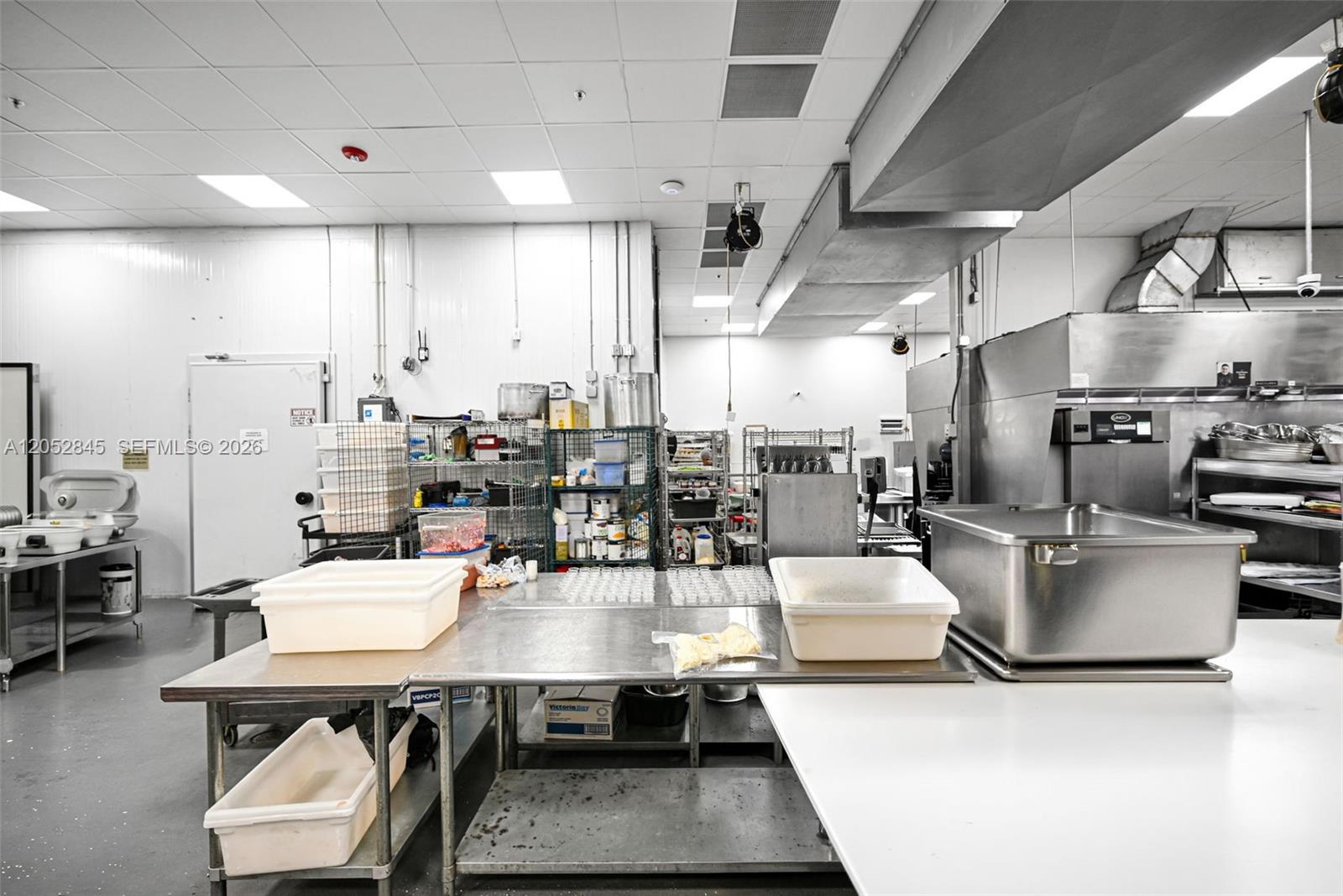 A commercial kitchen features stainless steel prep tables, industrial equipment, and white wall panels — 1395 E 11th Ave, Hialeah FL 33010, HIALEAH, FL