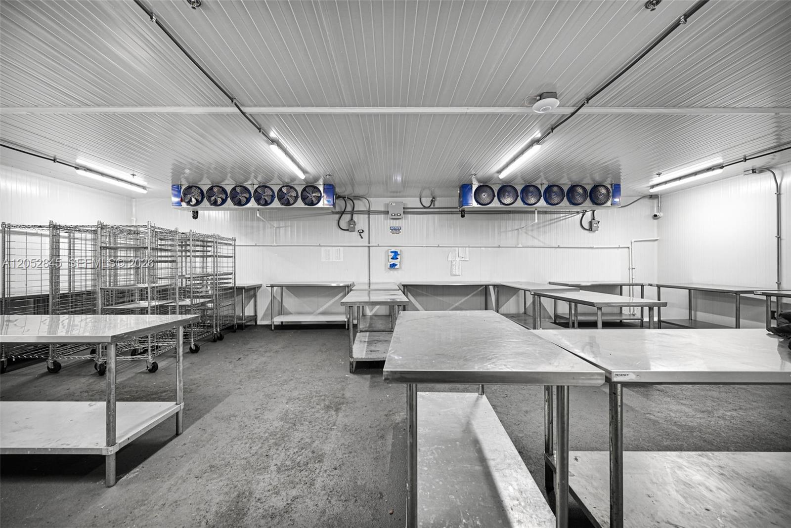 A commercial walk-in cooler features stainless steel prep tables, wire shelving units, and ceiling-mounted fans — 1395 E 11th Ave, Hialeah FL 33010, HIALEAH, FL