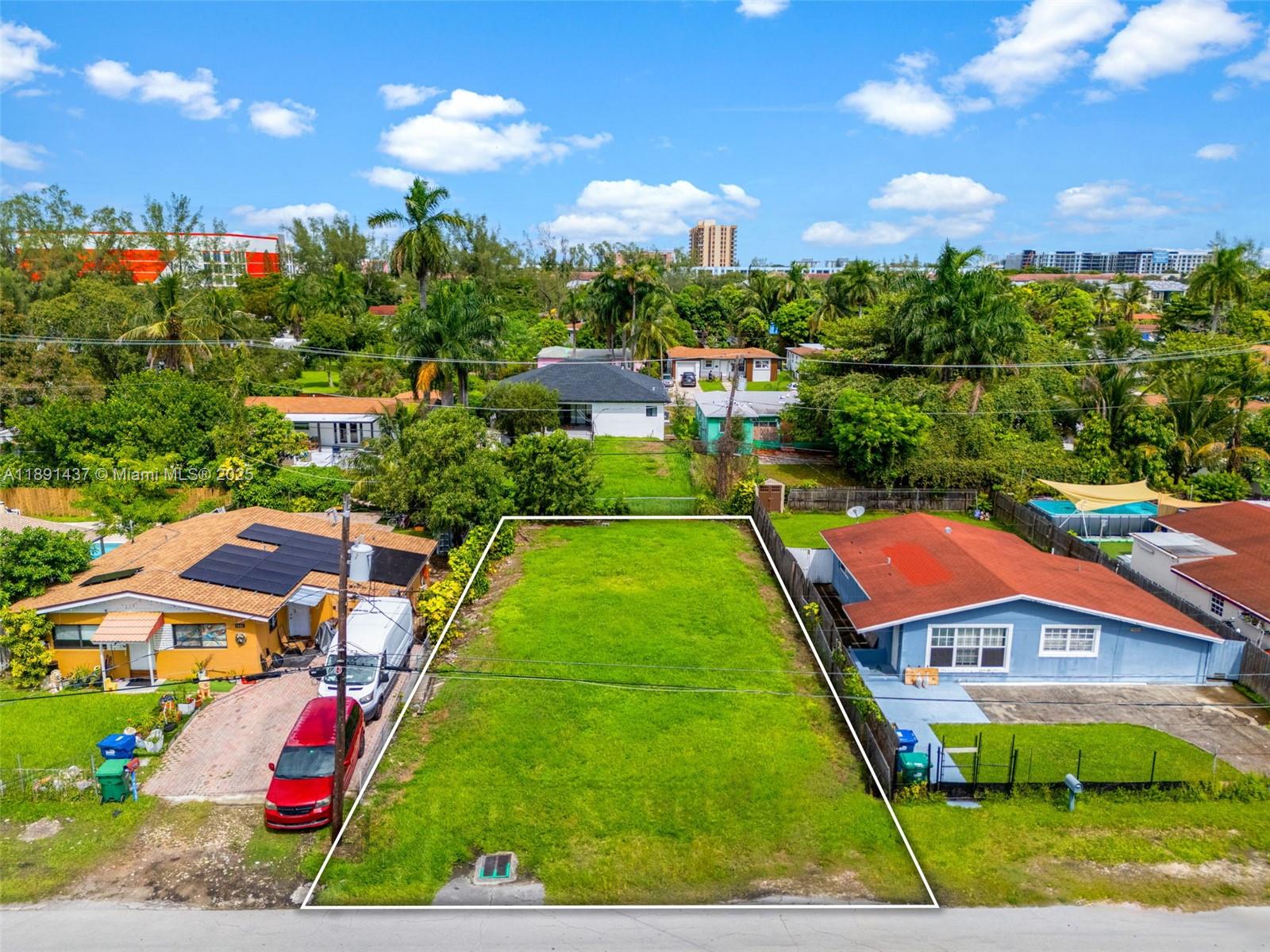 An aerial view shows a vacant rectangular grass lot situated between two residential houses — 1453 NE 117th St, Miami FL 33161, MIAMI, FL