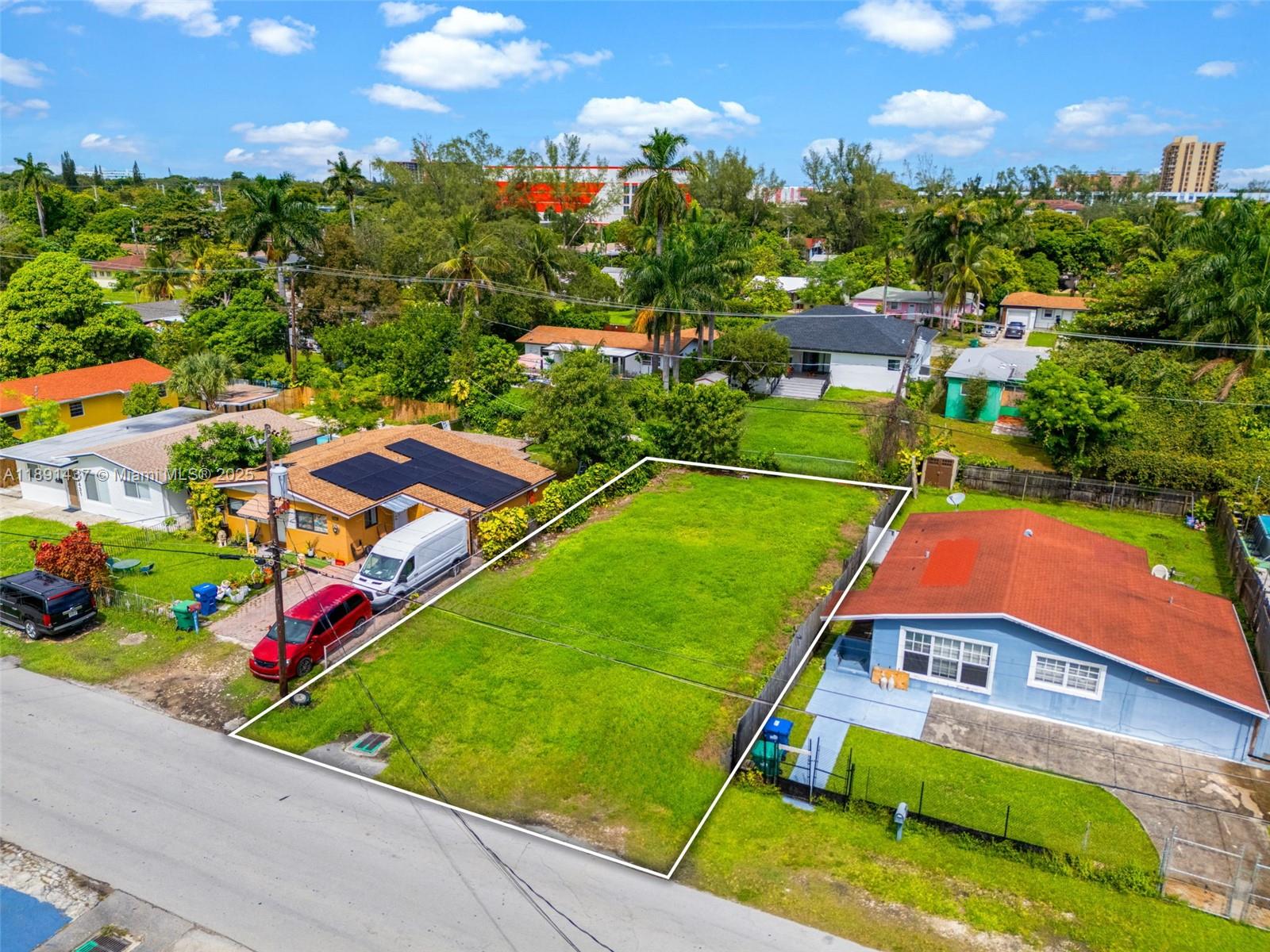 An aerial view shows a vacant rectangular grass lot situated between two residential houses — 1453 NE 117th St, Miami FL 33161, MIAMI, FL