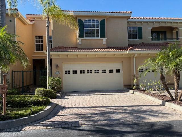 A two-story stucco townhouse features a two-car garage, a tiled roof, and palm trees — 3625 SQUARE WEST LANE UNIT 4, SARASOTA, FL